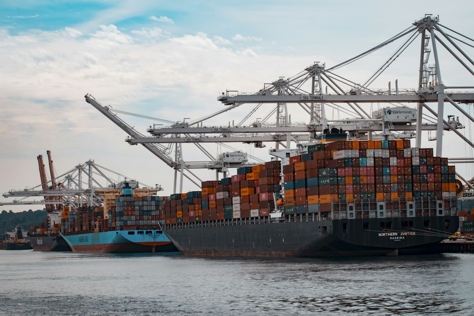 Cargo terminal at dusk with shipping containers under tracking lights